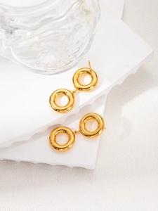 Close-up of gold geometric double round hoop earrings on a white decorative stone plate