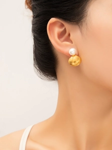 Detail shot of a model wearing a gold scallop earring with a white pearl accent