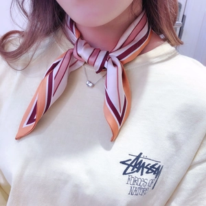 Detail of silk skinny scarf with geometric stripes tied around the neck as fashion accessory