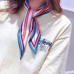 Close-up of a striped silk scarf tied in a cross knot around a model's neck