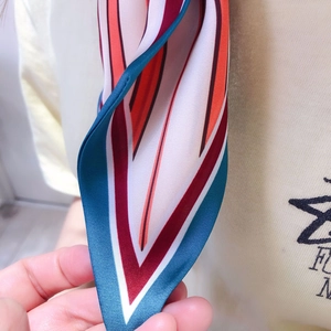Detail view of striped geometric silk scarf tip with vibrant red and navy satin finish