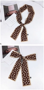 Détail d'un foulard étroit et soyeux à pois marrons pour un style élégant au cou