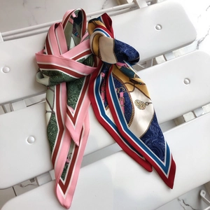 Detail of two patterned silk scarves with paisley and equestrian prints on a white bench