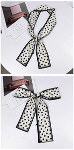 Détail d'un long foulard étroit en soie à pois noirs classiques et bordures noires fines