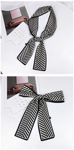 Détail d'un foulard étroit en satin avec motif à chevrons noir et crème élégant