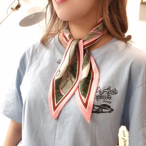 Detail of pink and green retro print silk scarf tied in a bow on a woman's neck