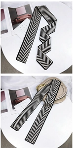 Détail d'un foulard en soie à chevrons noir et beige utilisé comme accessoire de sac chic