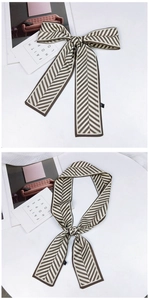 Détail d'un foulard étroit à motif chevrons marron et crème noué en nœud élégant