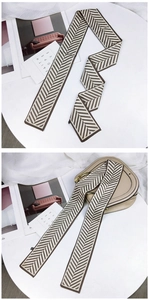 Détail d'un foulard twilly à chevrons noué sur un sac de selle beige élégant