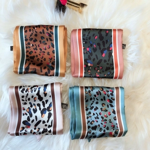 Close-up of four assorted leopard print polyester neck scarves on white faux fur