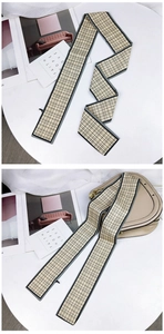 Gros plan d'une écharpe étroite à carreaux beige utilisée comme ruban sur un sac à main