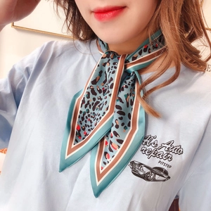 Close-up of a blue leopard print silk scarf styled as a neckerchief on a light blue T-shirt