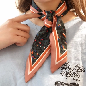 Detail of leopard print silk scarf with green and orange contrast border on neck