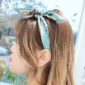 Detail of light blue silk hair ribbon with leopard print and dots tied in a bow