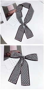 Vue détaillée du foulard étroit en soie à motif damier rose et noir noué en nœud élégant
