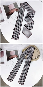 Détail d'un foulard en soie à carreaux rose et noir utilisé comme accessoire de sac élégant