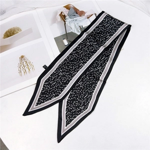 Detail of narrow black and white leaf print silk scarf with pointed ends on a magazine