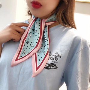 Detail of light blue silk scarf featuring puppy print and contrast pink border on neck