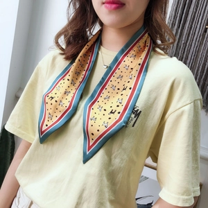 Detail of a beige twilly scarf with dog print and vibrant color-block striped edges