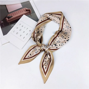 Detail of elegant beige silk twilly scarf with cute dog patterns and polka dots