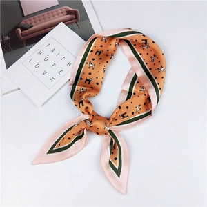 Detail of a silky orange twilly scarf with cute cartoon dog prints and green borders