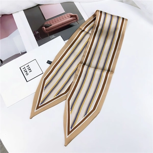 Detailed close-up of a striped silk scarf with pointed ends displayed on an aesthetic table