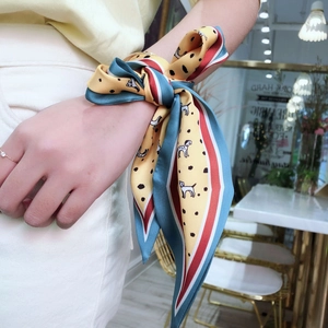 Versatile silk-like scarf with dalmatian print and colorful stripes worn as a wrist accessory
