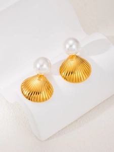 Detailed close-up of shell-shaped gold earrings with pearls on a white display stand