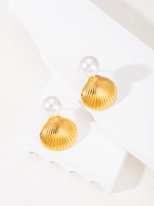 Macro shot of gold-plated seashell earrings with white pearls on a geometric stand