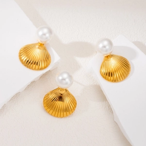 Elegant gold shell earrings with white pearl accents on minimalist stone display