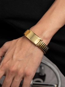 Close-up of a gold-plated stainless steel identity bracelet with elastic watch band style