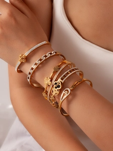 Close-up of stacked gold clover bracelets with zircon details on female wrist