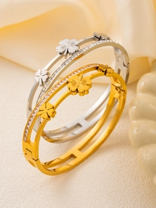Macro shot of 18k gold and silver clover bracelets featuring sparkling zircon stone inlay