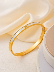 Détail d'un bracelet en acier doré avec incrustation de nacre et détails en zircone