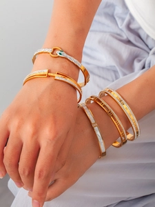 Gros plan de bracelets superposés en acier titane doré avec chiffres romains et cristaux
