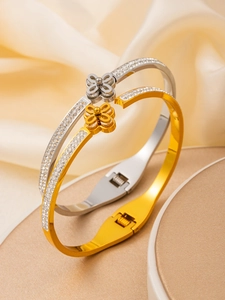 Detail of 18k gold and silver clover bracelets with zircon inlay on silk background
