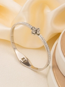 Detailed view of silver stainless steel bangle with pavé crystals and a central clover motif