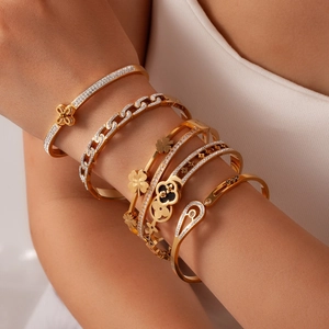 Stacked 18k gold plated clover bracelets and zircon bangles on a woman's wrist