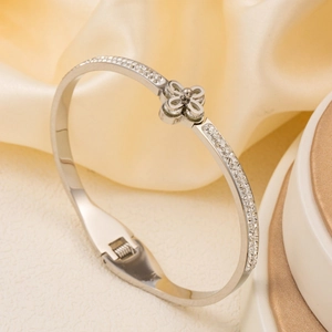 Polished silver stainless steel bangle with pavé rhinestones and hollow clover charm