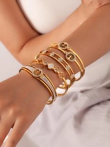 Detailed view of gold plated tree of life and clover bangles with zircon inlay on wrist