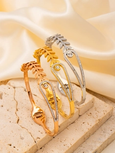 Close-up of three metal bangles with leaf textures and sparkling crystal droplets