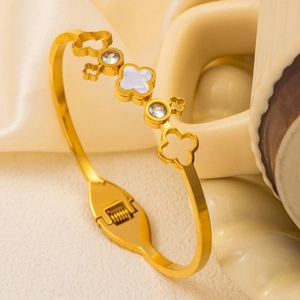 Gold stainless steel clover bangle with shell inlay and cubic zirconia on silk background