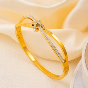 Elegant rose gold bow bangle with pave zircon stones on a luxurious satin backdrop