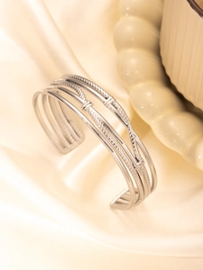 Detail showing the layered silver steel bangle with braided and smooth textures on silk