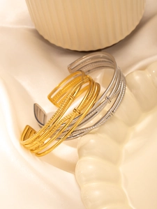 Detailed view of layered C-shape titanium steel cuff bracelets in gold and silver
