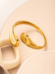 Macro view of polished golden stainless steel cuff bangle with modern teardrop design