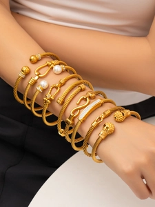 Dettaglio di bracciali a cavo dorati con teschio punk e dettagli in perla