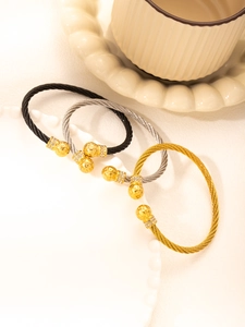 Three twisted cable bangles in gold, silver, and black with zircon encrusted spheres
