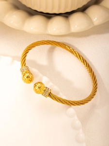 Close-up of gold cable wire bracelet with hammered sphere ends and zircon accents