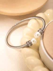 Macro detail of silver twisted cable bracelet featuring faux pearls and crystal accents
